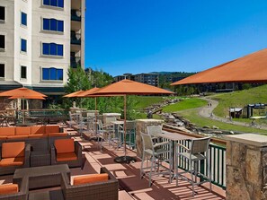 A rooftop patio with outdoor seating, umbrellas, and a view of a hilly landscape. - Steamboat Springs | Mountain Ski | Ski Access & Hot Tub (Steamboat Springs)