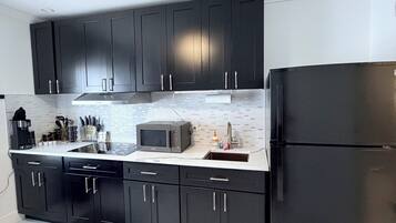 A modern kitchen with black cabinets, a stainless steel refrigerator, and a microwave.