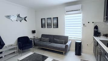 Un salon moderne avec un canapé, une table basse, un ventilateur de plafond et un décor mural représentant des poissons.