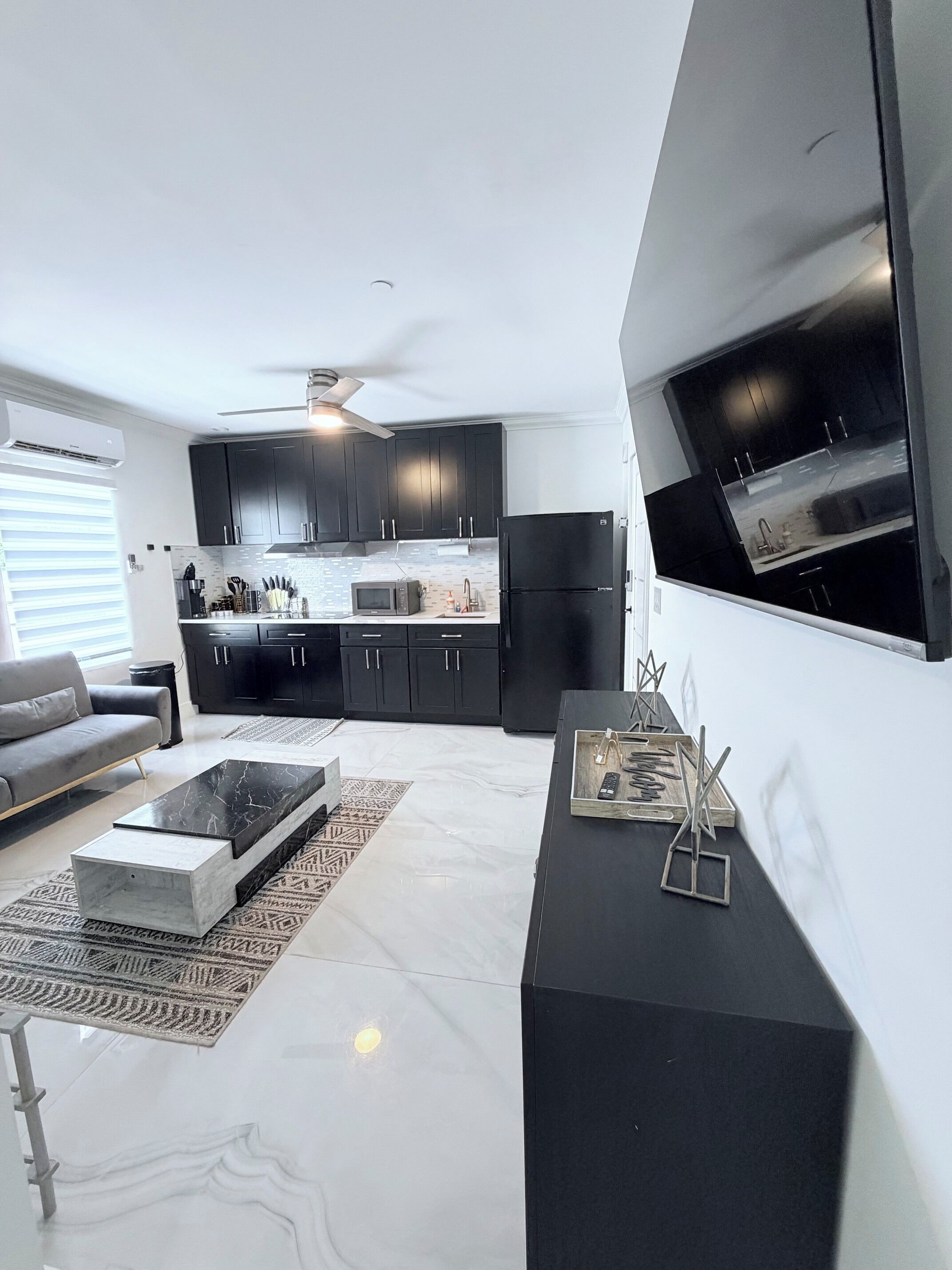 A modern living room with a sofa, coffee table, and a TV mounted on the wall.