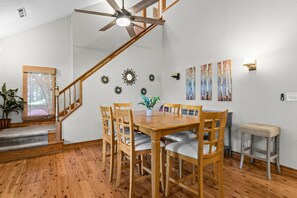 A dining area with a wooden table and chairs, a ceiling fan, and a staircase. - Lake Oconee Retreat | Hot Tub, Dock & Kayaks (Eatonton)