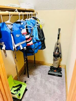 A closet with hanging bags and a vacuum cleaner. - Lake Oconee Retreat | Hot Tub, Dock & Kayaks (Eatonton)