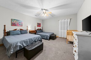 A bedroom with two beds, a desk, a chair, a TV, and a ceiling fan. - Lake Oconee Retreat | Hot Tub, Dock & Kayaks (Eatonton)