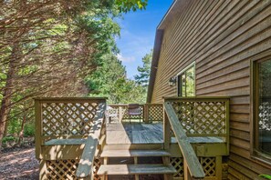 A wooden deck with a lattice railing, leading to a building with a window and a door. - Lake Oconee Retreat | Hot Tub, Dock & Kayaks (Eatonton)
