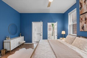 A bedroom with a bed, a dresser, a mirror, and a door leading to a bathroom. - Fun Grove Stay – Walk to Bars, Restaurants & BJC (St. Louis)
