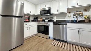 Una cocina moderna con electrodomésticos de acero inoxidable, armarios blancos y suelo de madera.