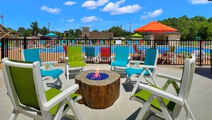 Un espacio al aire libre con sillas y una chimenea, con vistas a una piscina.