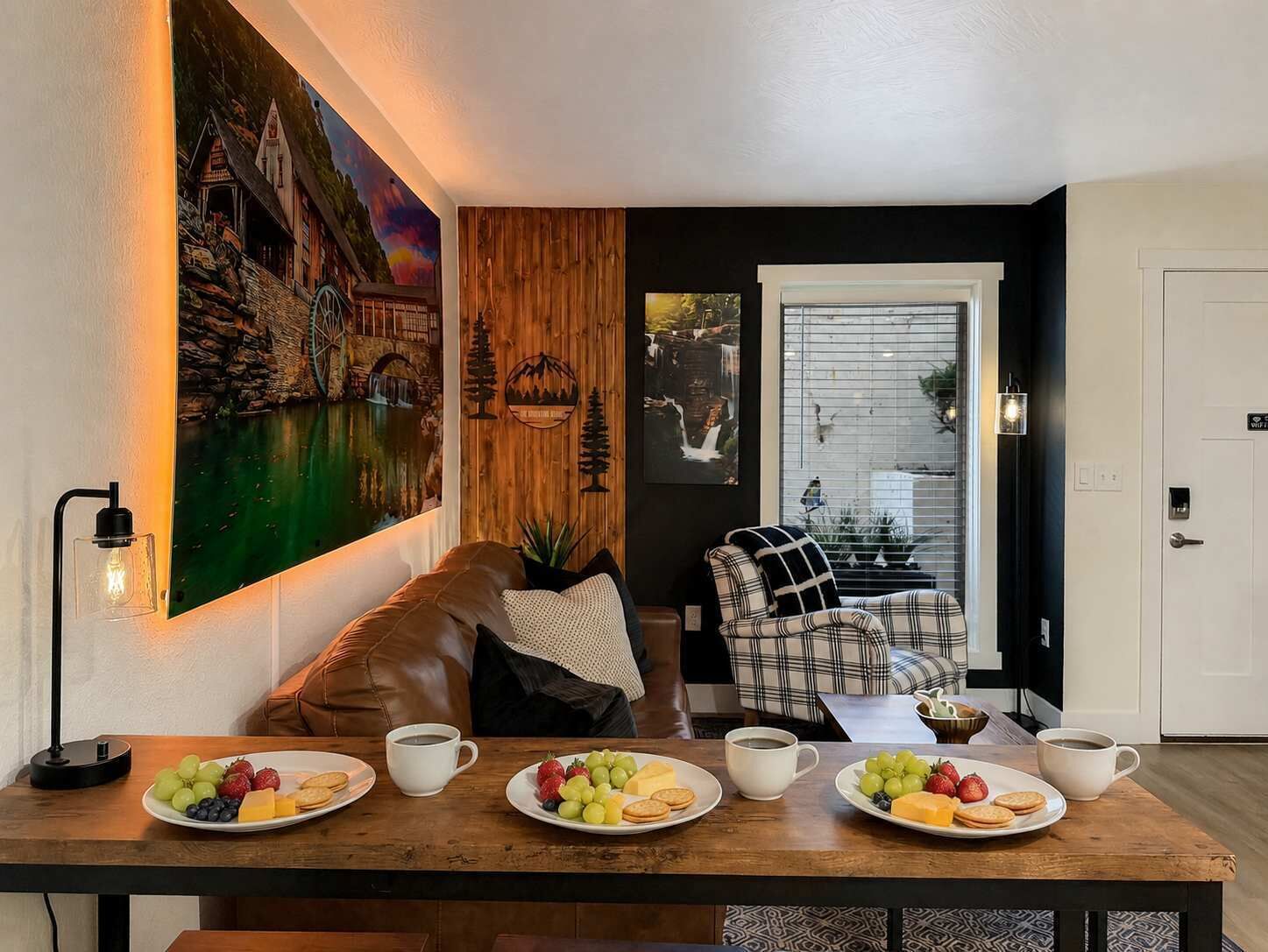 Un coin repas avec une table en bois dressée pour le petit-déjeuner, un tableau accroché au mur et une vue par la fenêtre.