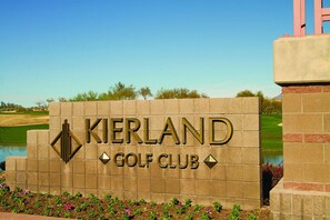 A sign for KIERLAND GOLF CLUB with a clear view of a golf course in the background. - Scottsdale | Group Desert Escape | Pool + Golf | 2BR (Scottsdale)