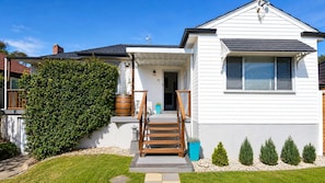 A two-story house with a front porch, a wooden staircase, and a well-maintained lawn. - Central Bell, Slp`s 8, Refurbished Heart of Newca (Adamstown Heights)