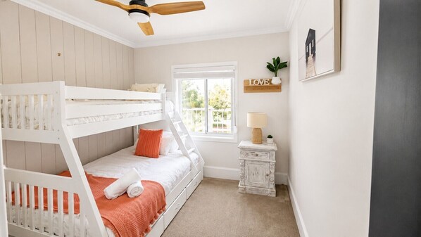 A child's bunk bed with a window, a small table with a lamp, and a 'LOVE' sign on the wall.