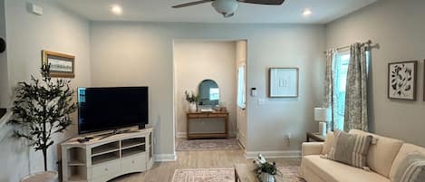 A living room with a flat-screen TV, a ceiling fan, a sofa, a coffee table, and a patterned rug.