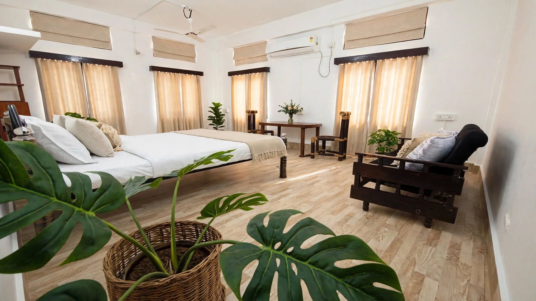 Et hotelværelse med en seng, en sofa, et lille bord og en potteplante.
