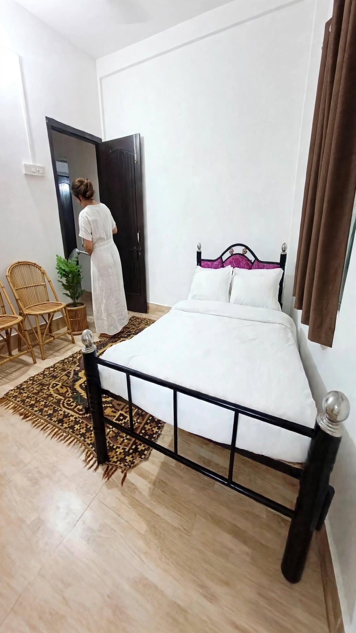 Una camera da letto con un letto, una sedia, una pianta in vaso e una porta.