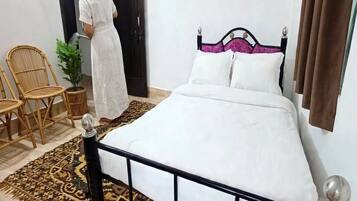 Una camera da letto con un letto, una sedia, una pianta in vaso e una porta.