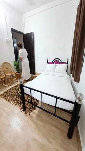 Un dormitorio con cama, una silla, una planta en maceta y una puerta.