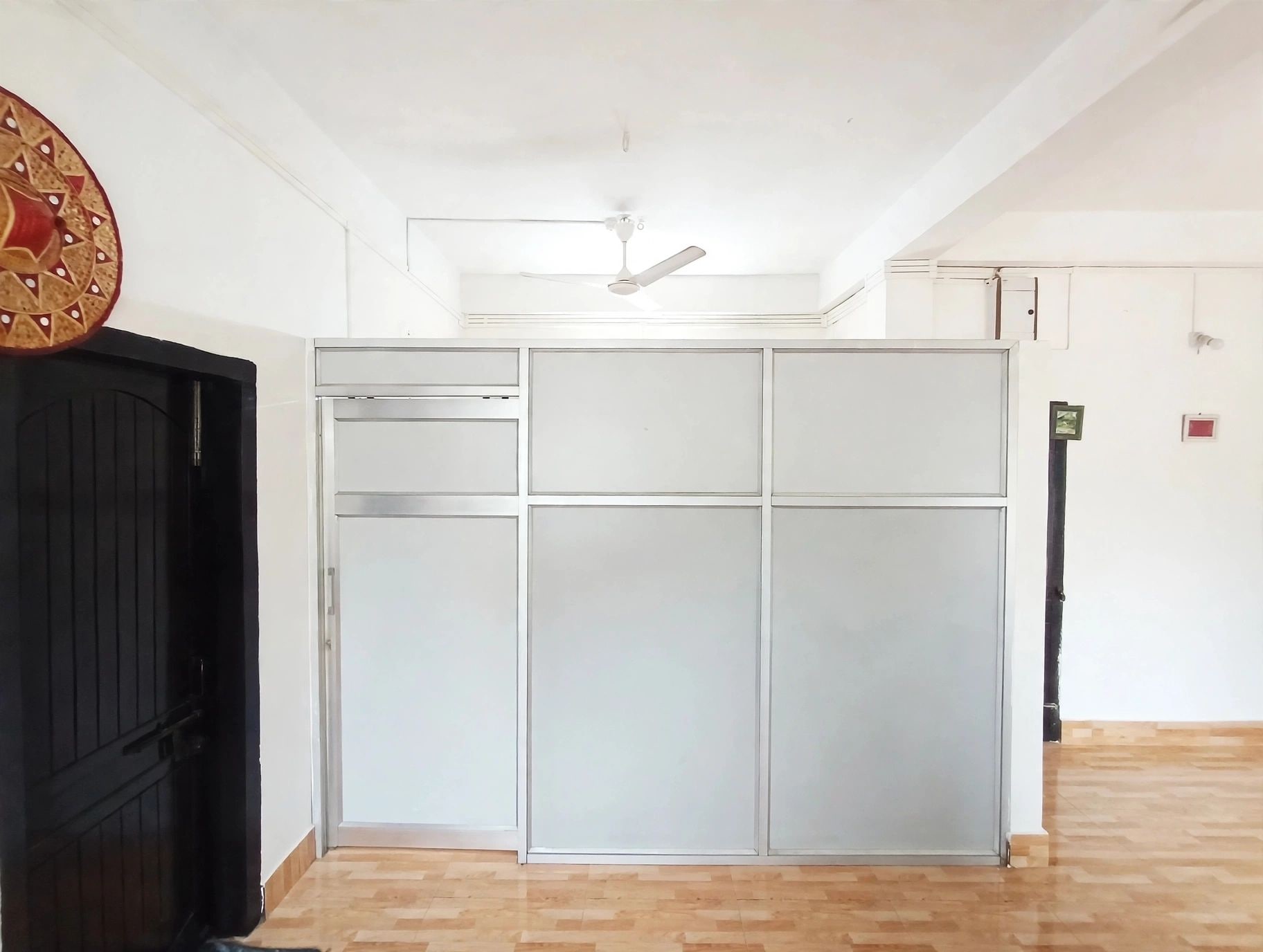 Una habitación con puerta corredera, ventilador de techo y suelo de madera.