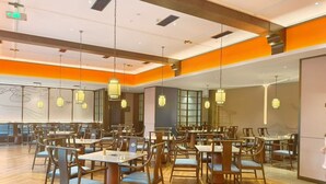 A spacious dining area with multiple tables and chairs, overhead lighting, and a modern interior design.