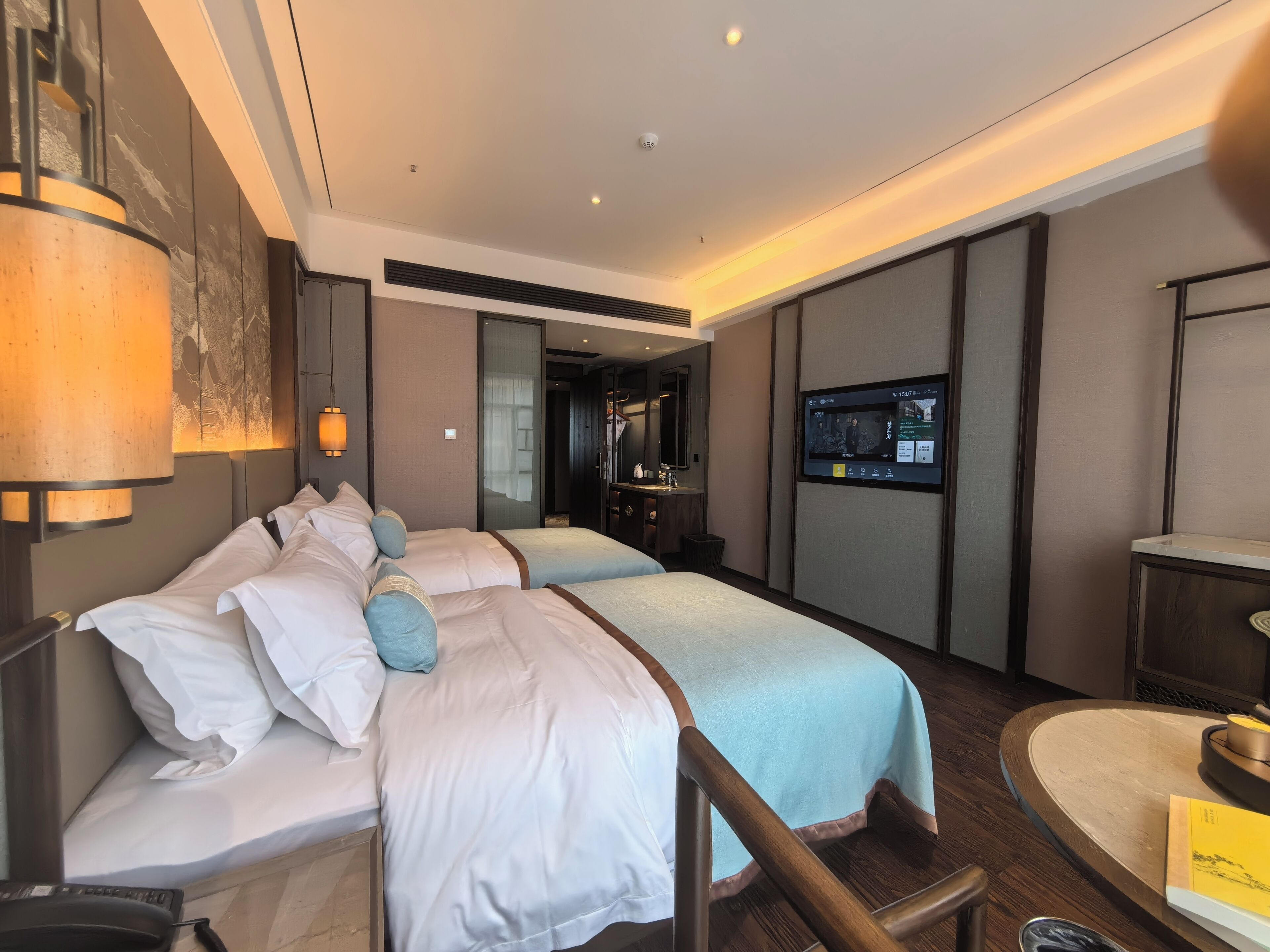 A hotel room with two beds, a TV, a desk, and a chair.