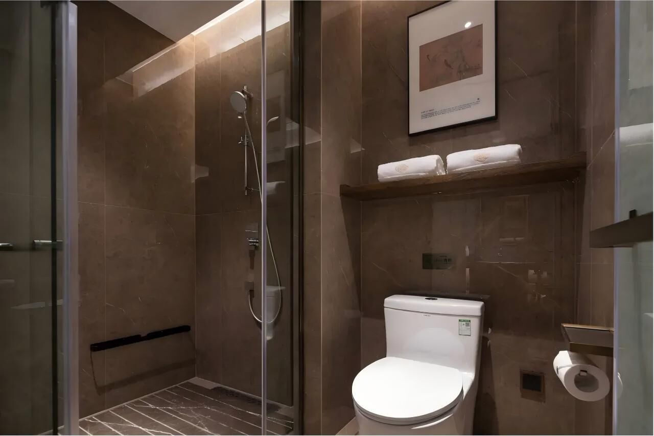 Une salle de bain moderne avec une douche à parois de verre, des toilettes et une étagère avec des serviettes.