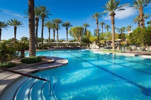 A swimming pool with palm trees and lounge chairs.