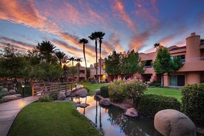 Ein Hotelinnenhof mit Wasserspiel, Palmen und Abendhimmel.