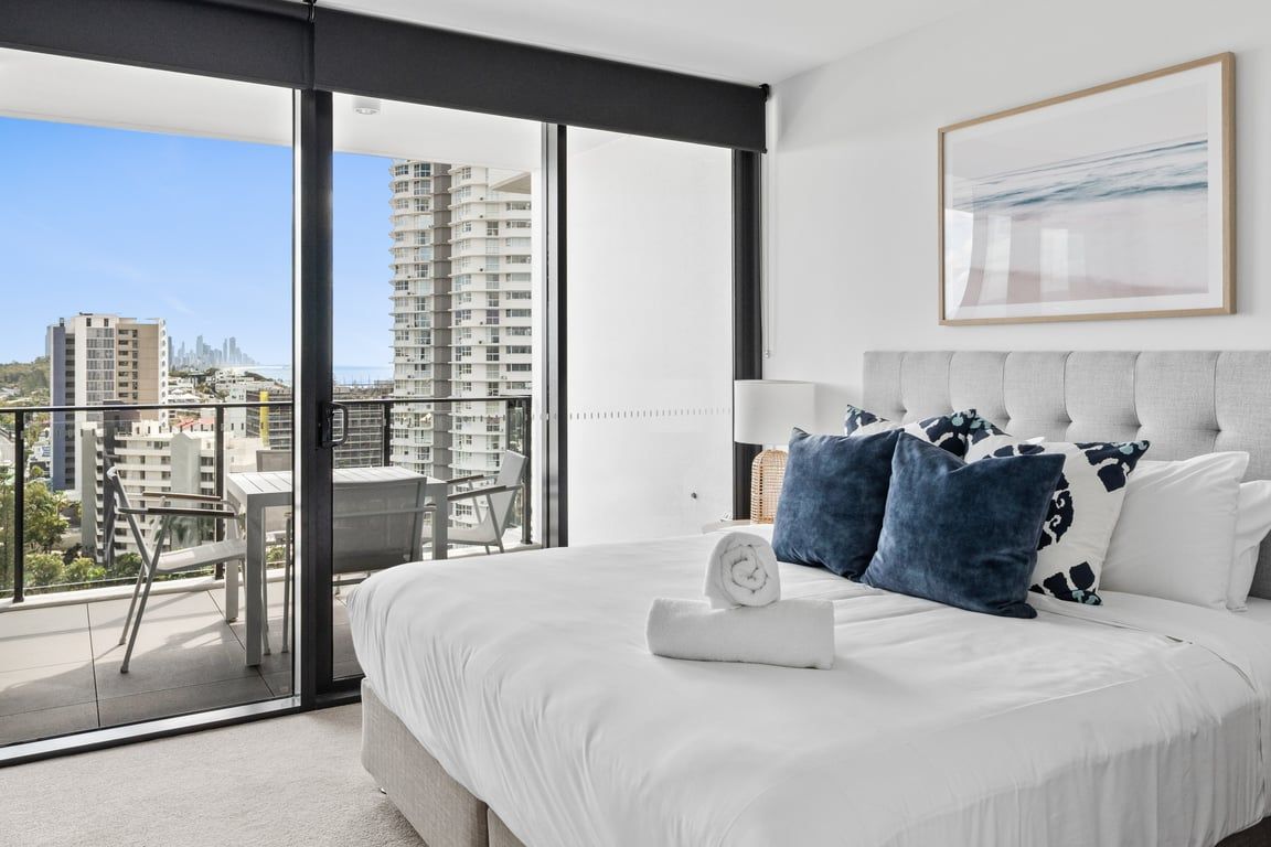 Habitación de hotel moderna con una cama grande, vistas a la ciudad y un balcón.