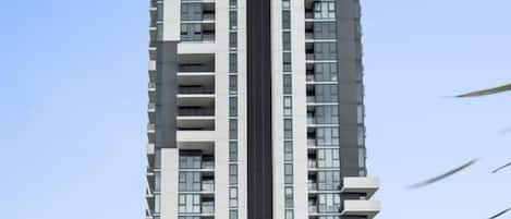 Un edificio de gran altura con varios pisos, un elemento vertical central y un escaparate en la base.