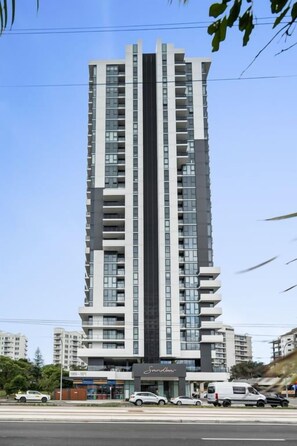 A high-rise building with multiple floors, a central vertical feature, and a storefront at the base. - Sandbar 80 - (2BR/2BA) (Gold Coast)