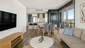 Ein modernes Wohnzimmer mit Flachbildfernseher, rundem Couchtisch und einer Couch.
