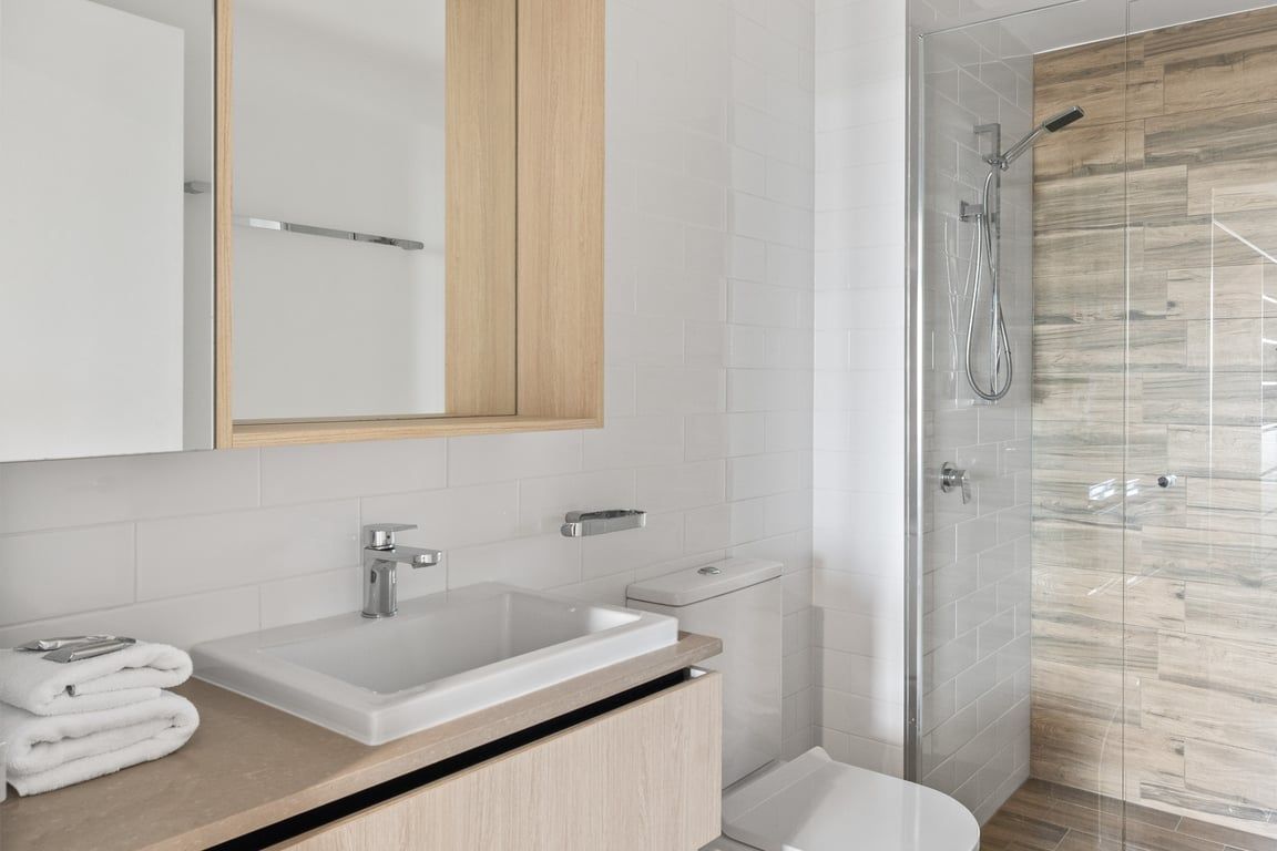 A modern bathroom with a large sink, a toilet, and a glass shower enclosure.