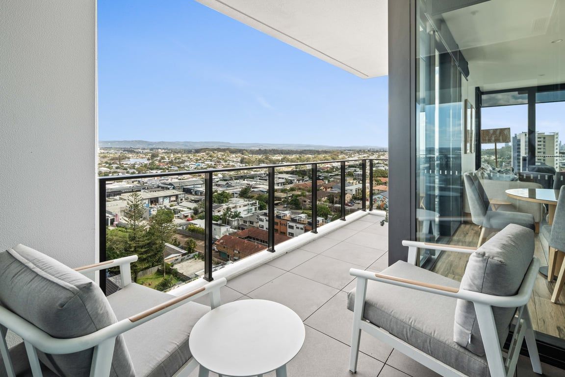 A balcony with a city view, furnished with chairs and a table.