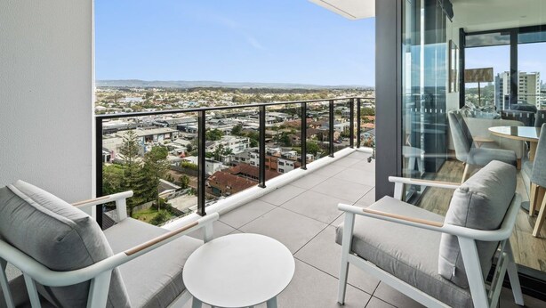 Ein Balkon mit Blick auf die Stadt, möbliert mit Stühlen und einem Tisch.
