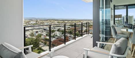 A balcony with a city view, furnished with chairs and a table.