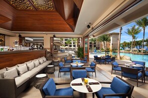 A spacious outdoor lounge area with seating arrangements, a poolside view, and a bar area. - Maui | Couples Island Weekend | Pool + Beach (Lahaina)