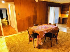 A dining area with a table set for four, surrounded by wooden chairs, a patterned tablecloth, and a carpeted floor. - Vintage East Dallas 3 King Bed Retreat • Fire Pit • Grill Near White Rock Lake (Dallas)