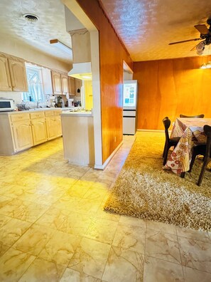 A spacious kitchen with wooden cabinets, a central island, and a dining area with a table and chairs. - Vintage East Dallas 3 King Bed Retreat • Fire Pit • Grill Near White Rock Lake (Dallas)
