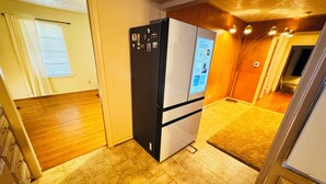 Una cocina compacta con refrigerador, piso de madera y un ventanal pequeño.