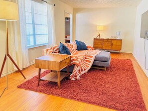 A cozy bedroom with a bed, a small table, a red rug, and a wooden cabinet. - Vintage East Dallas 3 King Bed Retreat • Fire Pit • Grill Near White Rock Lake (Dallas)