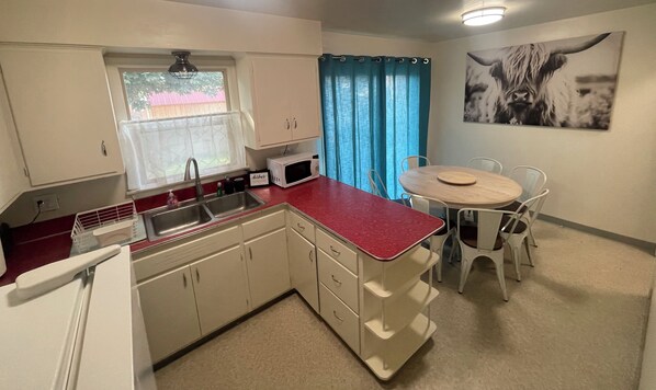 A compact kitchen with a sink, microwave, and dining area with chairs and a table. - Upstairs 3-bedroom House in Beautiful Pocatello. (Pocatello)
