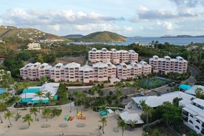 A resort with multiple buildings, a beach area with umbrellas, and a view of the sea. - St. Thomas | Tropical Beach Retreat | Pool + Beach (St. Thomas)