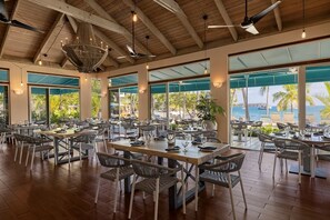 Un restaurante con terraza, amplias ventanas y vista al mar.