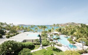 A resort with a swimming pool, palm trees, and a view of the ocean. - St. Thomas | Tropical Beach Retreat | Pool + Beach (St. Thomas)