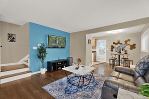 Ein Wohnzimmer mit blauer Akzentwand, einem flachbildfernseher über einem weißen Couchtisch und einem Ledersofa.