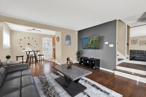 Een moderne woonkamer met een leren bank, een salontafel en een flatscreen televisie aan de muur.