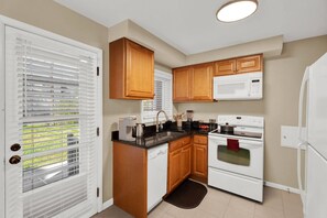 A kitchen with wooden cabinets, a white microwave, a stove, and a dishwasher. - 4BR Across 2 Adjacent Units - Downtown Birmingham (Birmingham)