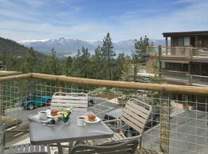 Ein Balkon mit Tisch für zwei Personen, mit Blick auf eine gebirgige Landschaft.