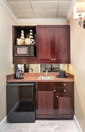 A compact kitchen with dark wood cabinets, a microwave, a coffee maker, and a dishwasher. - Seattle | Peaceful Courtyard Stay | Gym + Walkable (Seattle)
