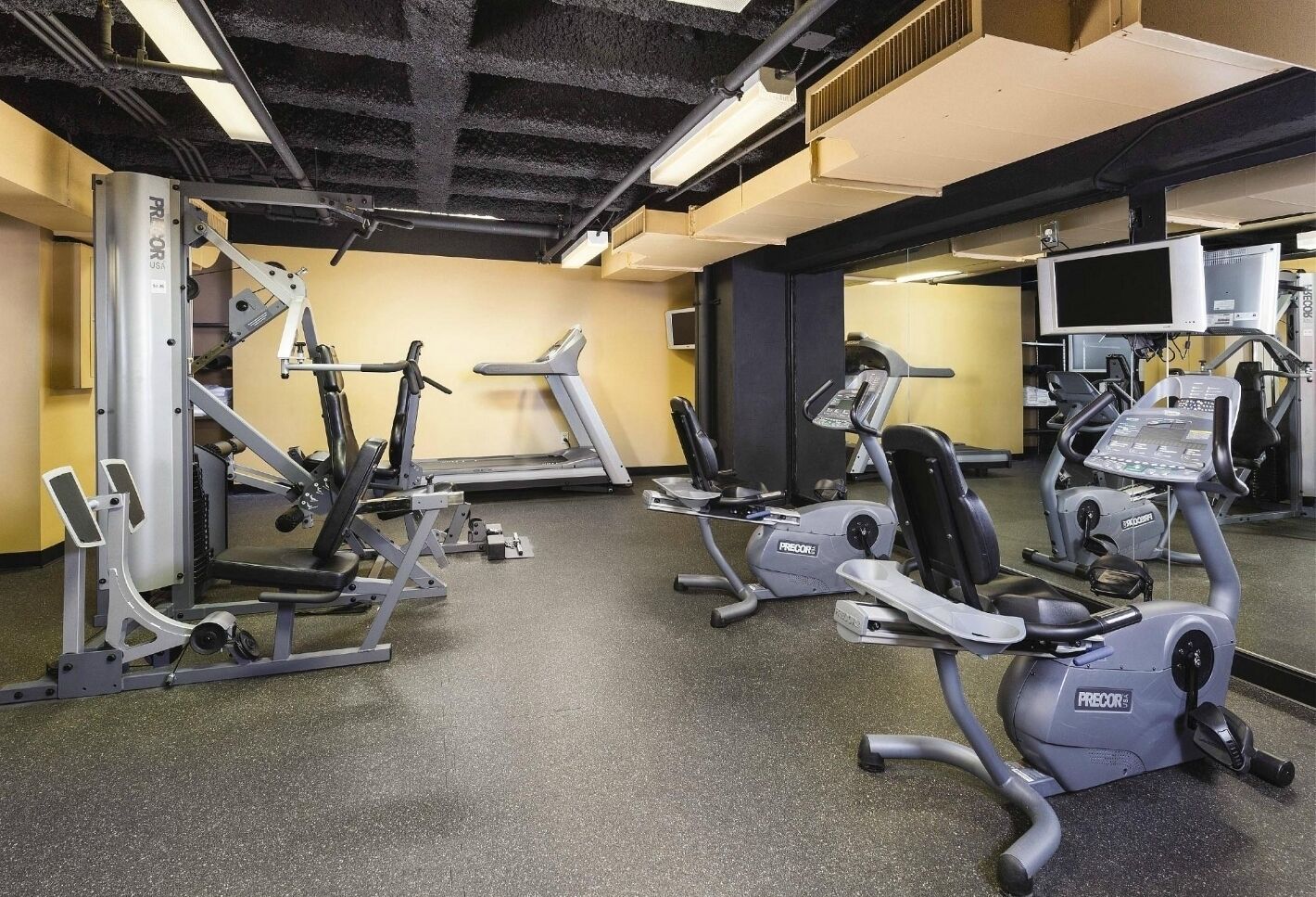 A gym with various exercise equipment including treadmills, weight machines, and a rowing machine.