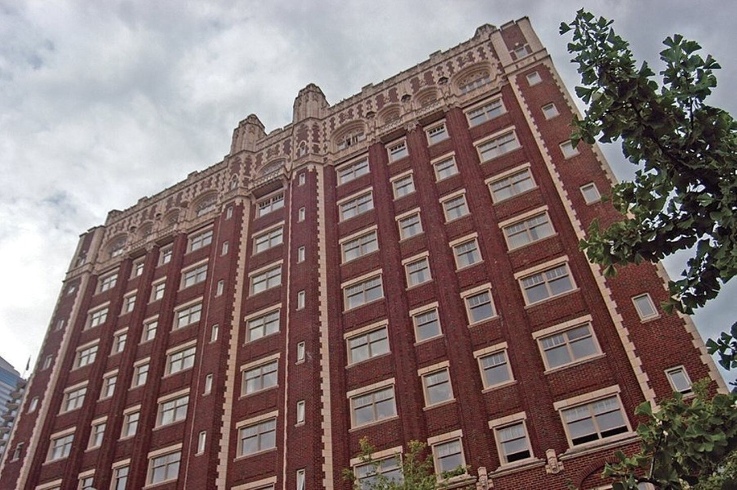 A tall brick building with multiple windows and a decorative facade.